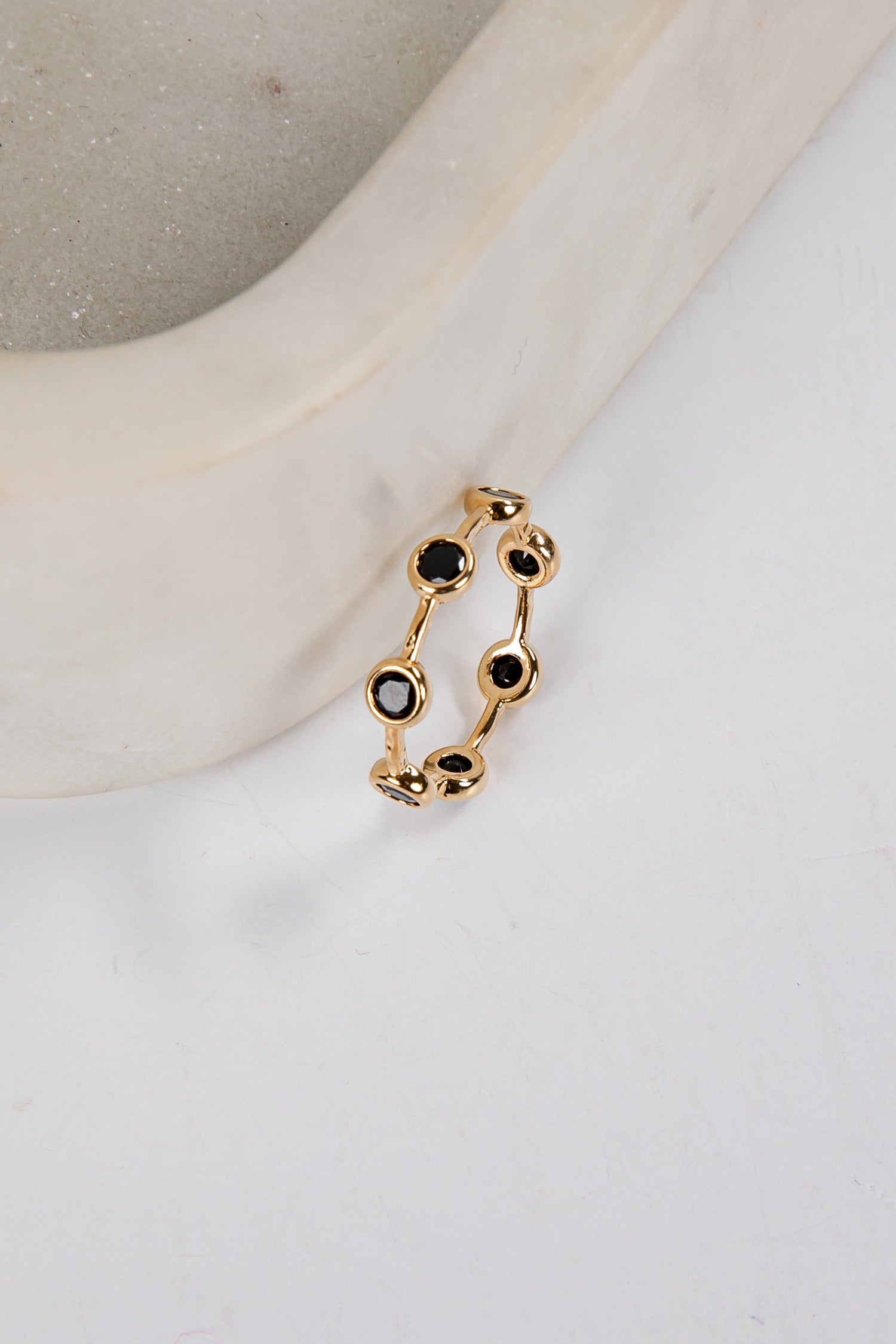 Gold ring with black gemstones on a white surface