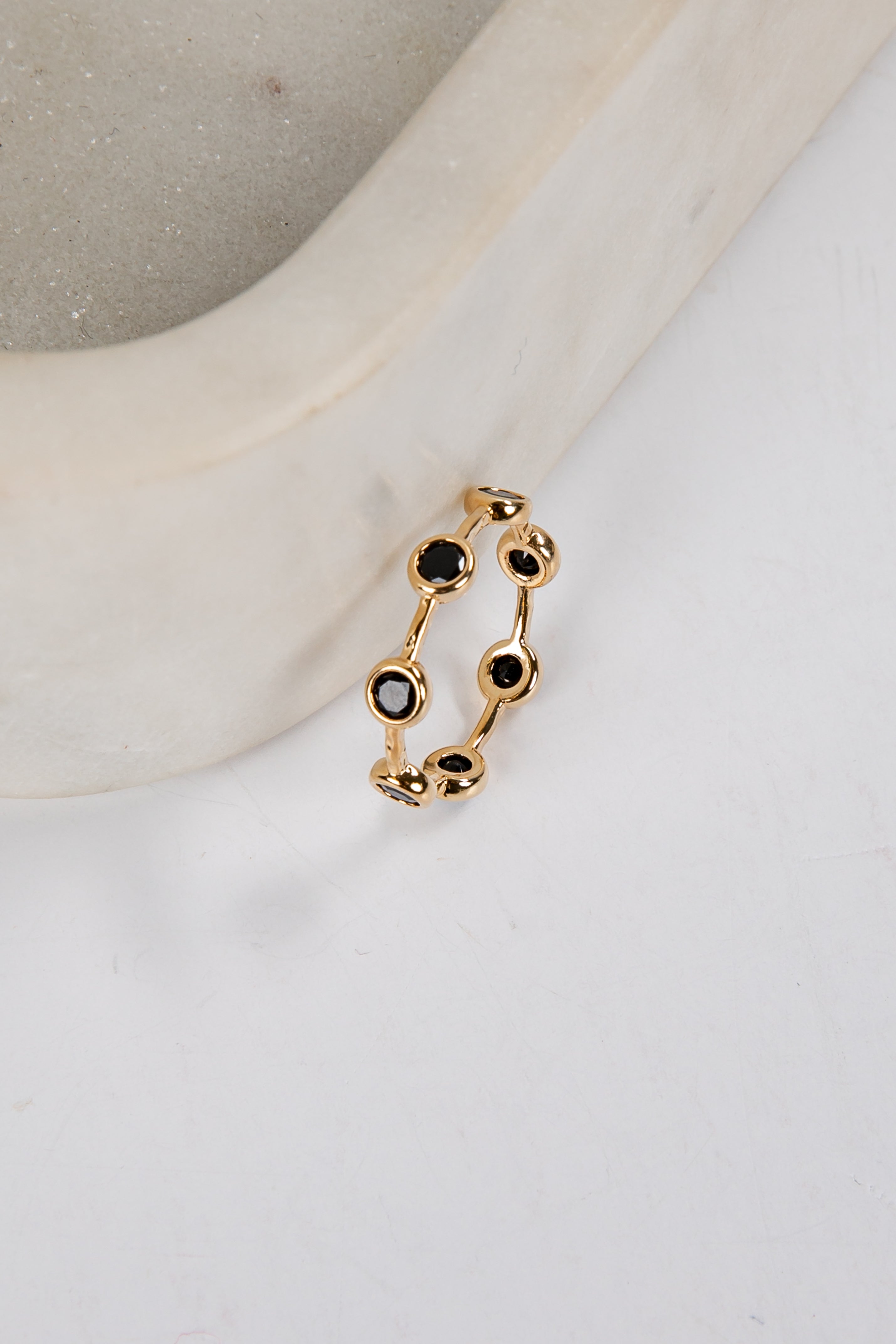 Gold ring with black gemstones on a white surface