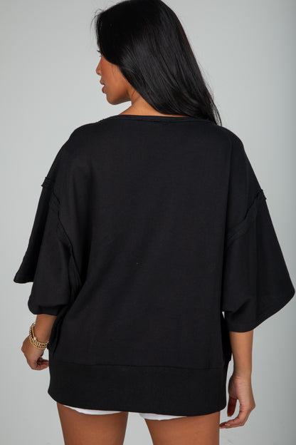 Person wearing a black oversized top and shorts on a gray background