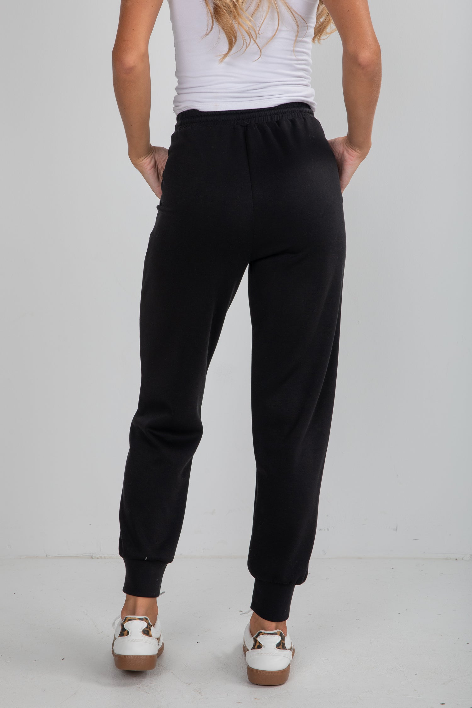 Person wearing black sweatpants on a plain background