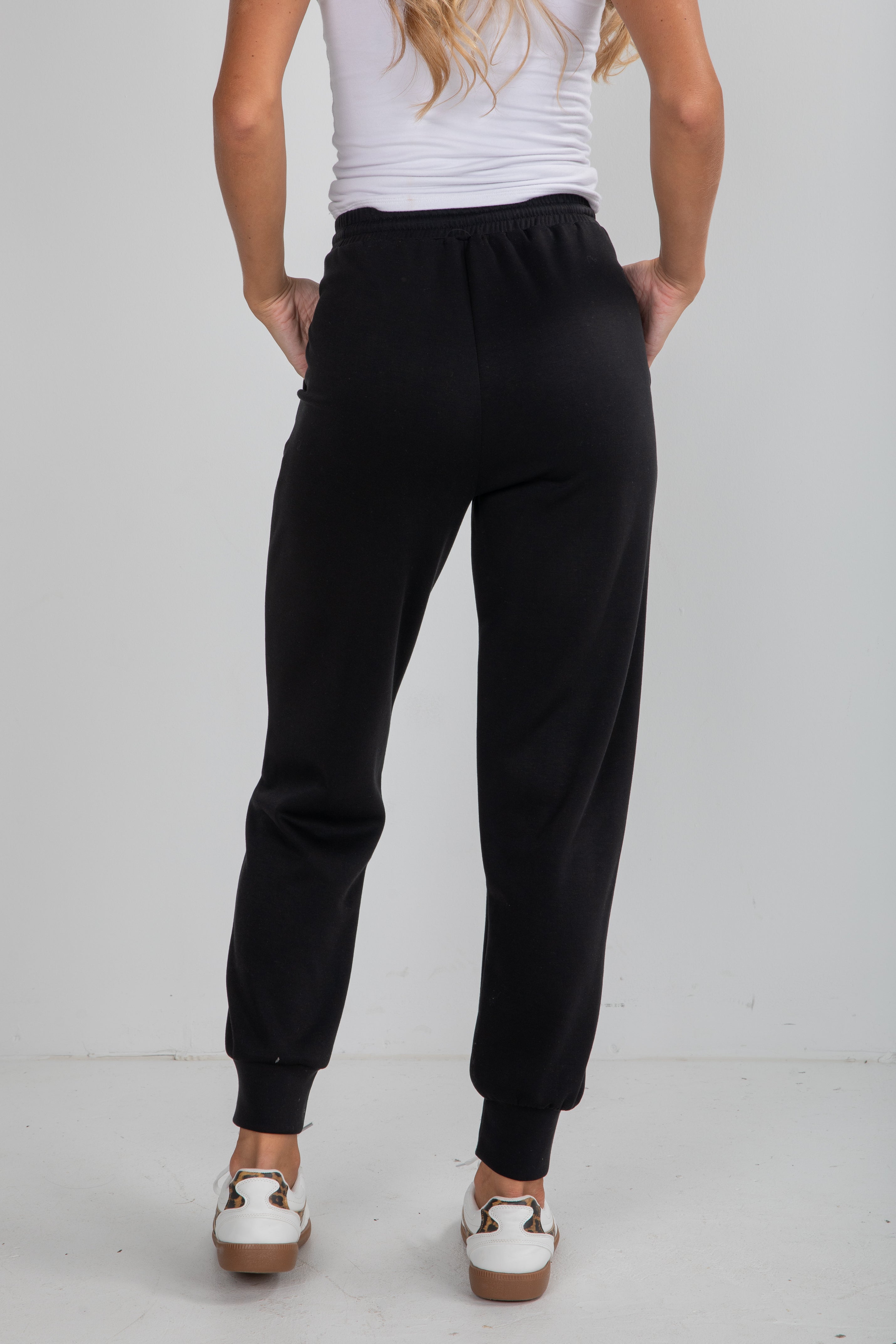 Person wearing black sweatpants on a plain background