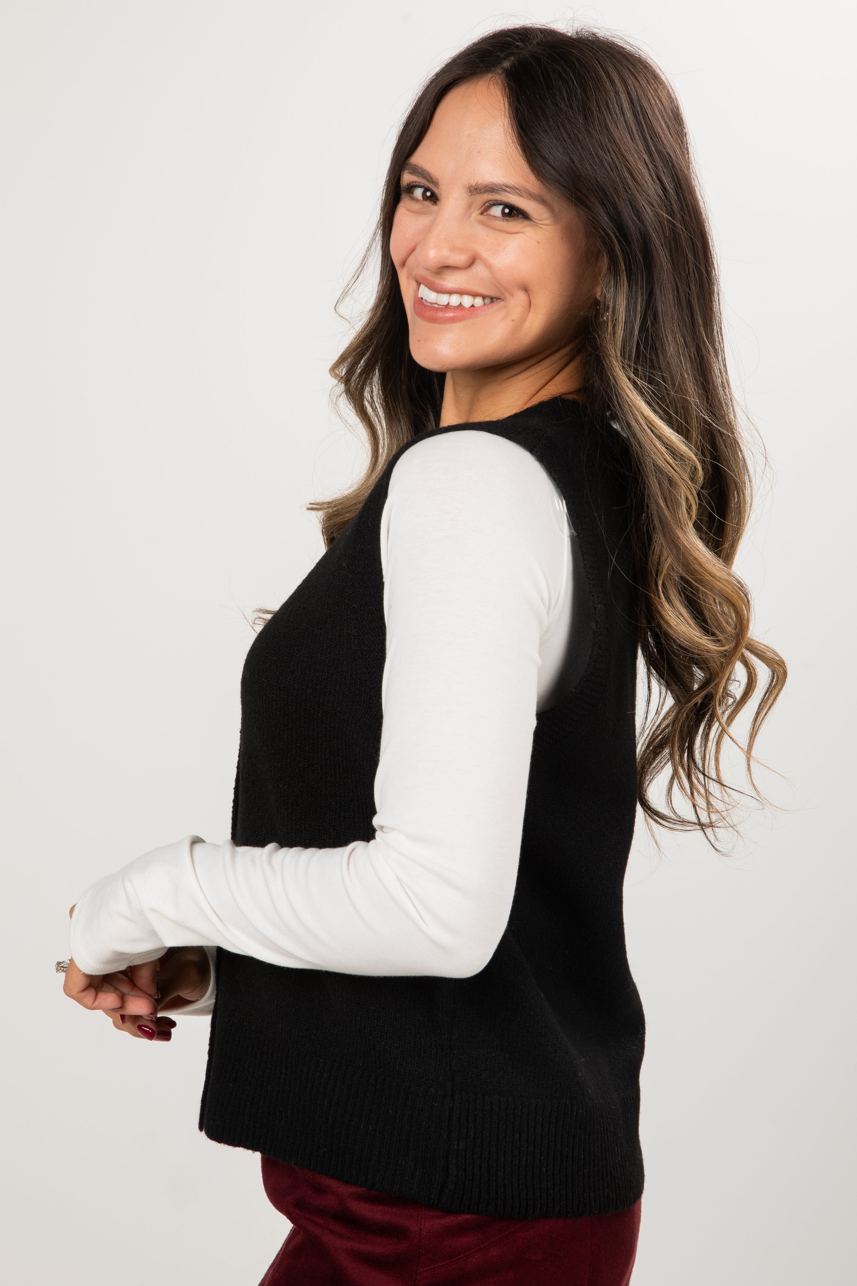Woman wearing a black sweater with white sleeves on a plain background