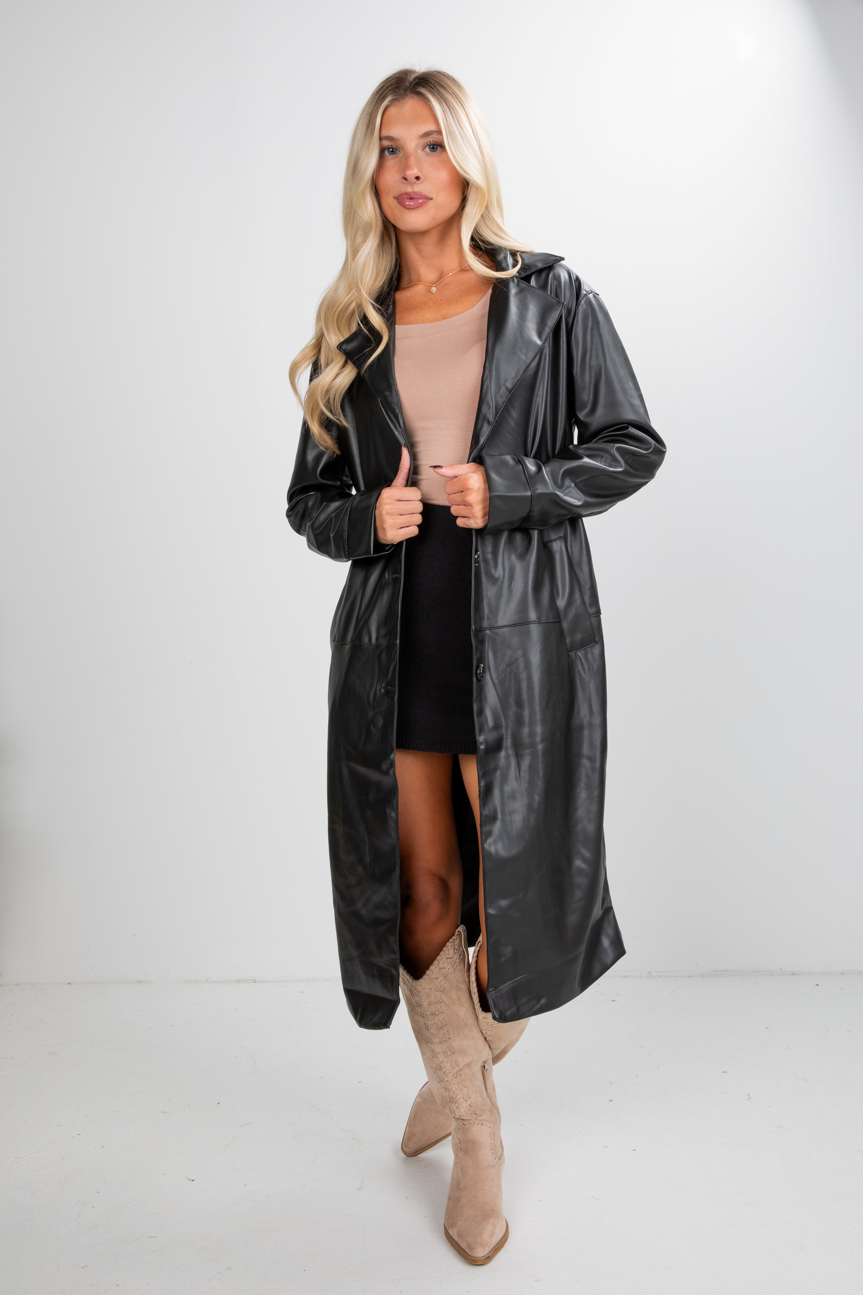Woman wearing a black leather trench coat on a white background