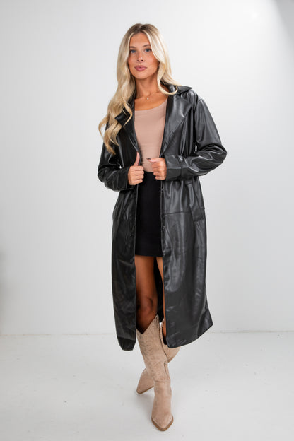 Woman wearing a black leather trench coat on a white background