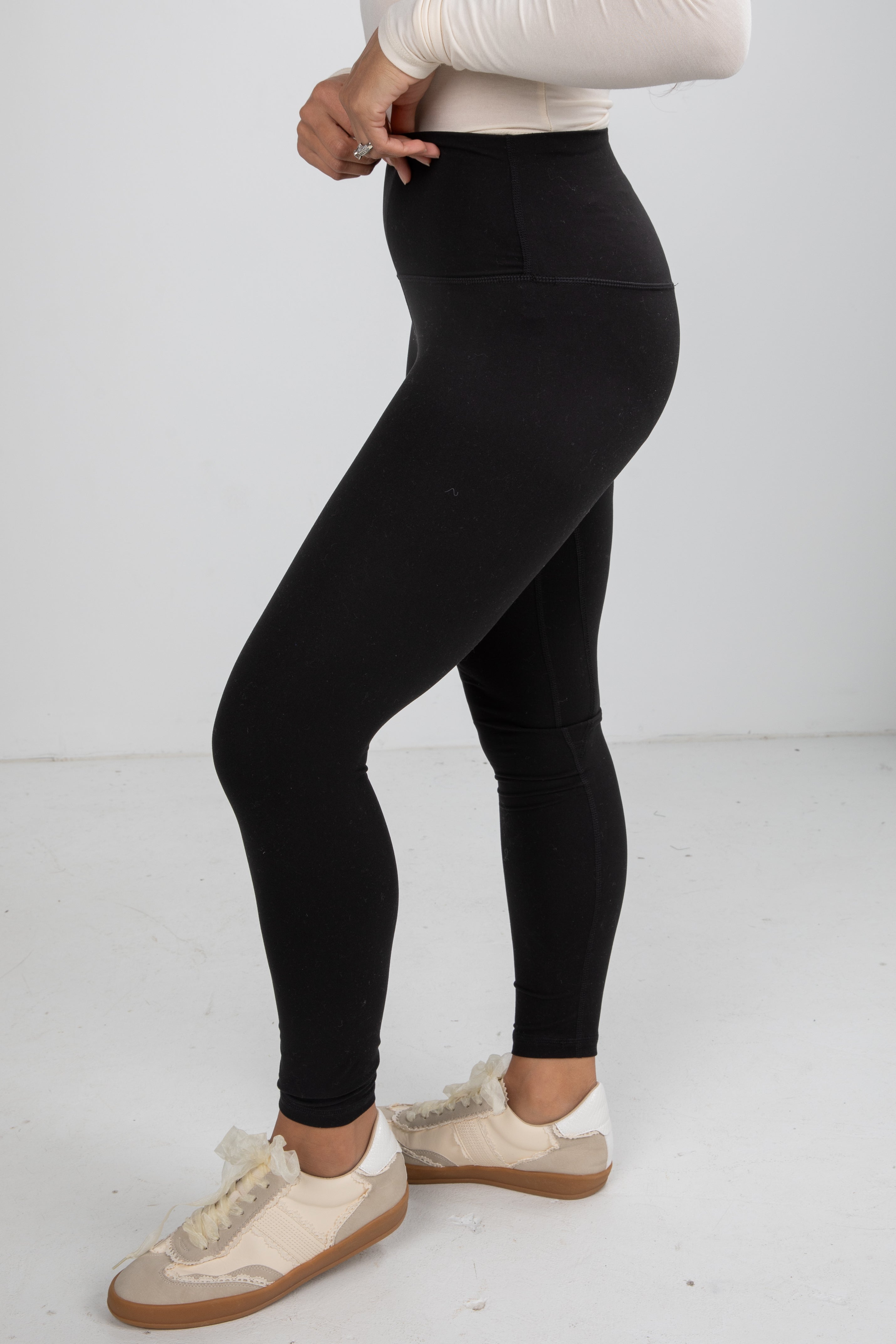 Person wearing black leggings with a plain white background