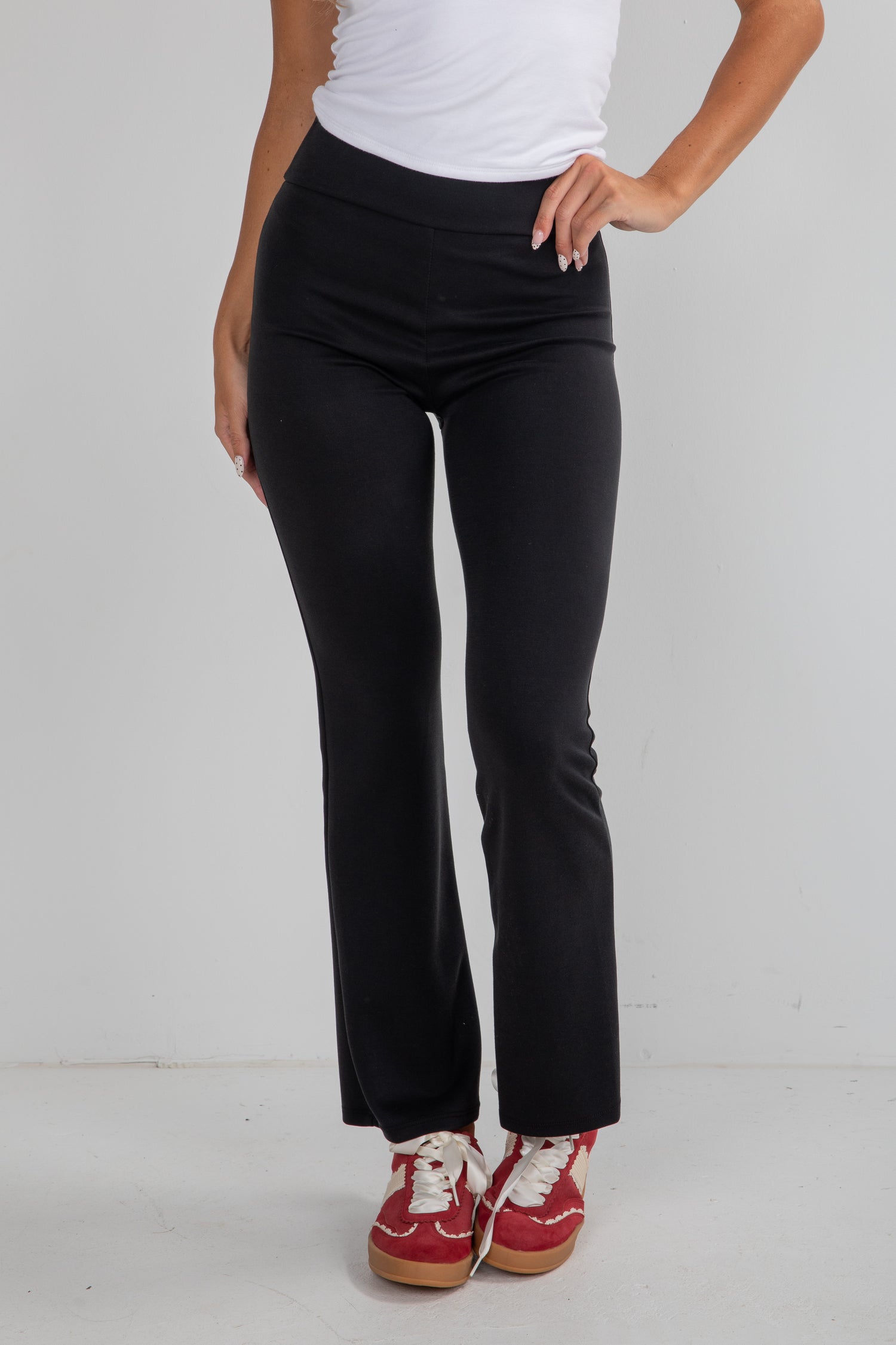 Person wearing black pants and red shoes on a white background