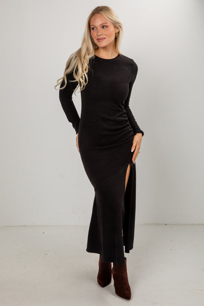 Woman wearing a black long-sleeve dress with a slit on a white background