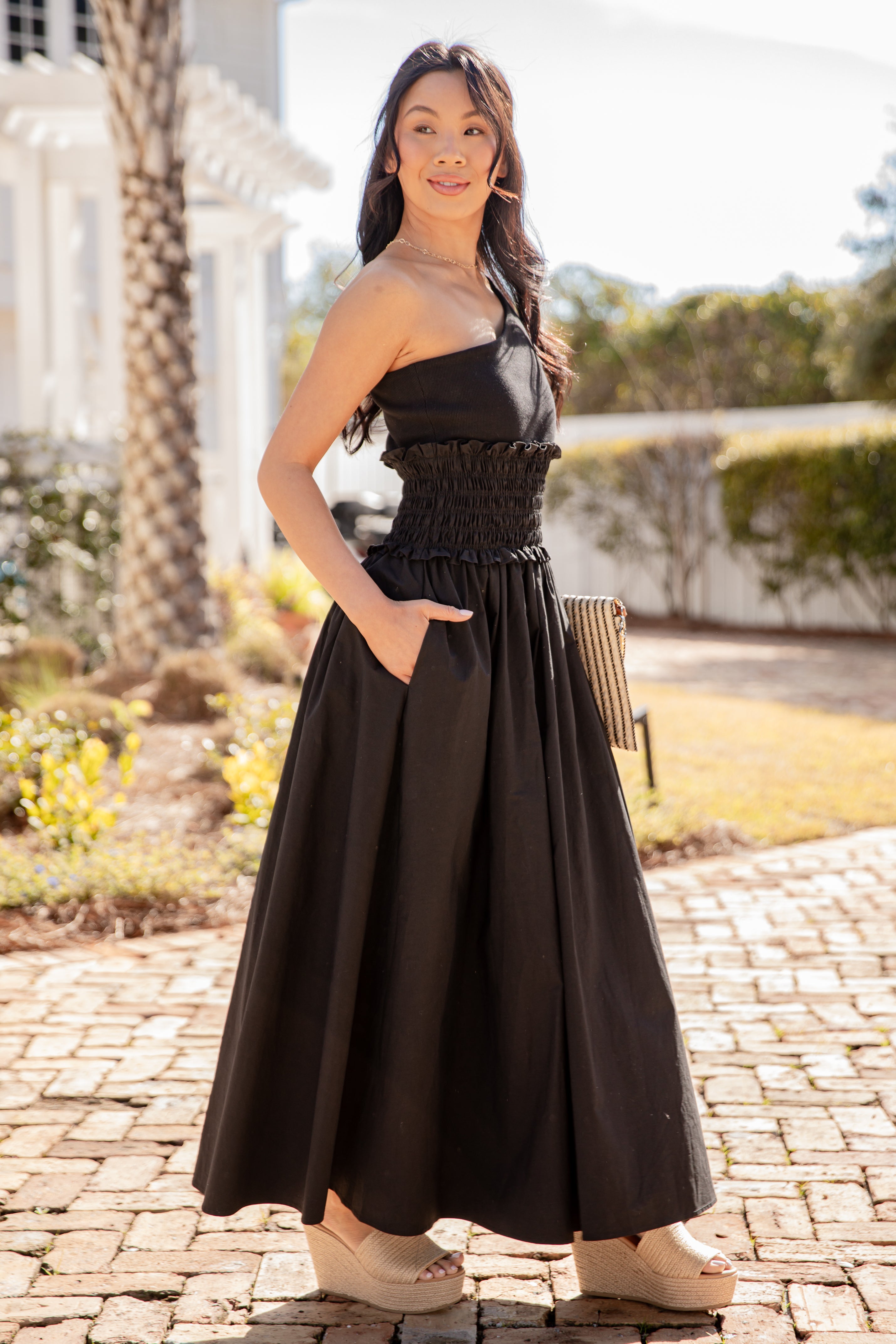 Woman in a black dress standing outdoors on a sunny day.