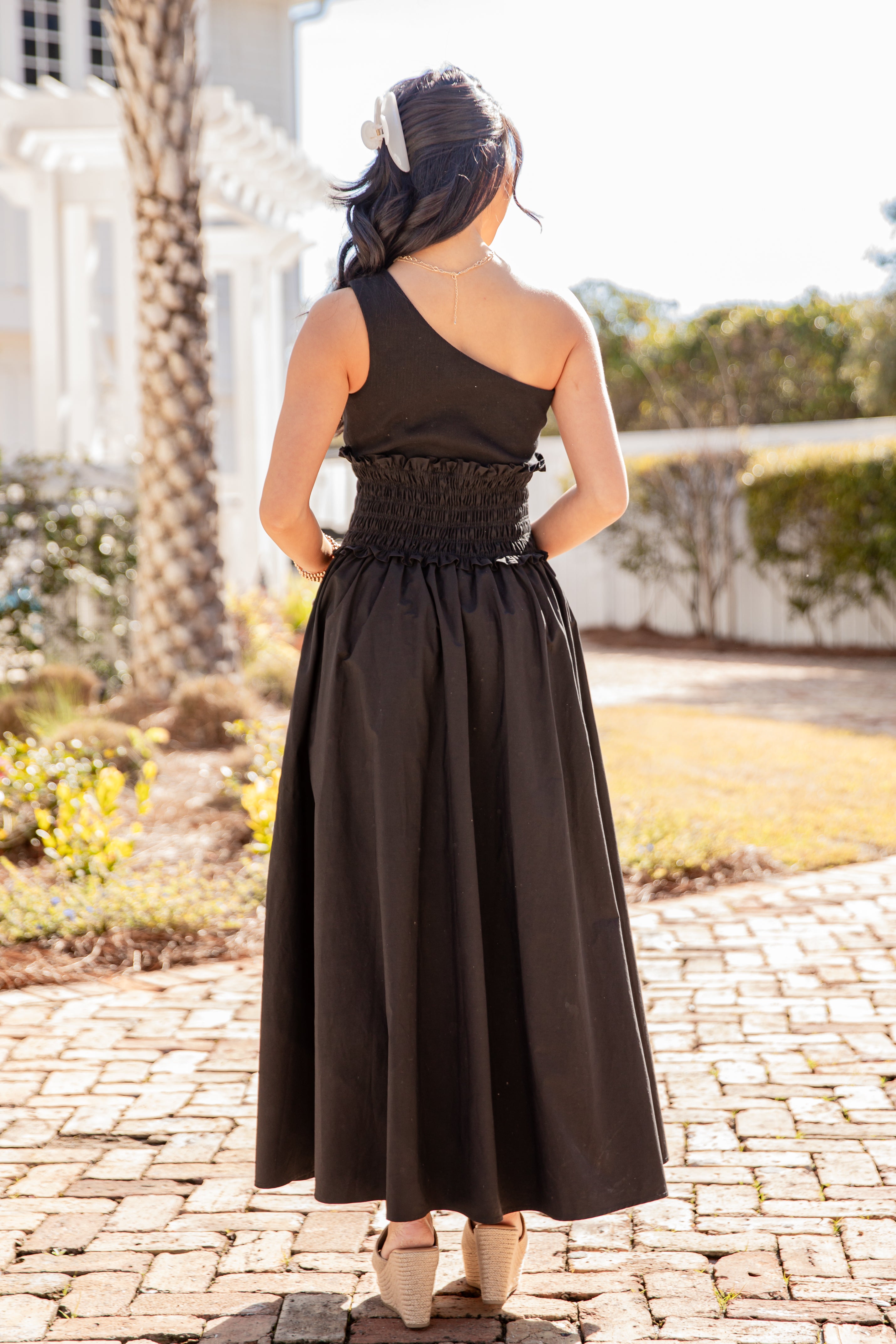 Woman wearing a black dress with a lace waist in an outdoor setting