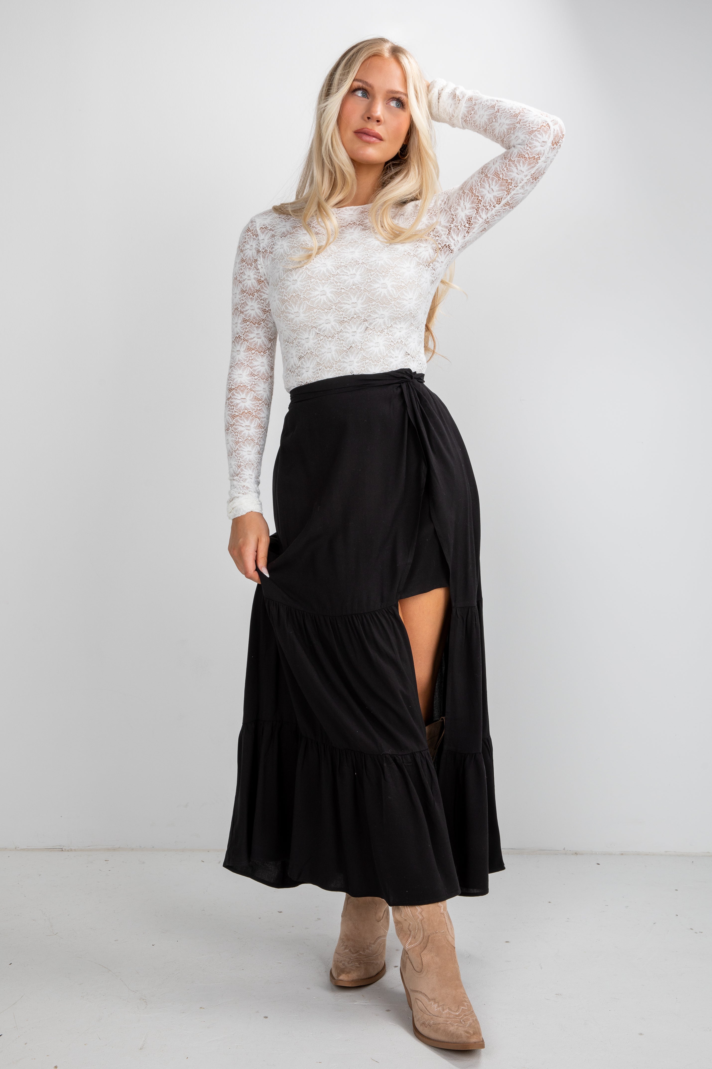 Woman wearing a white lace top and black skirt on a white background