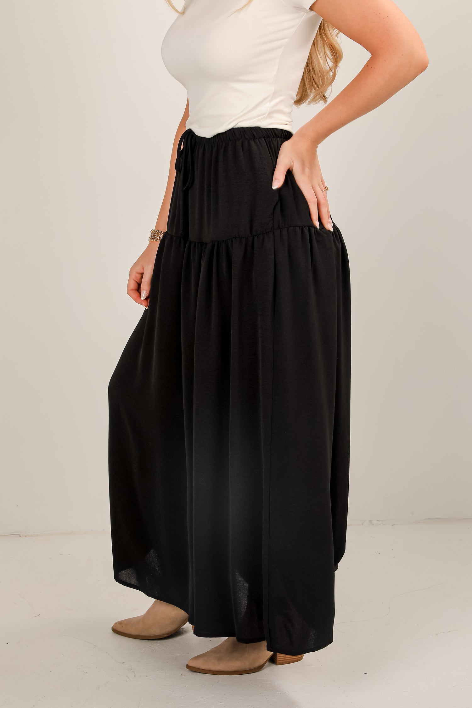 Person wearing a white top and black wide-leg pants on a plain background