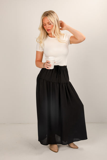 Woman wearing a white top and black skirt against a plain background