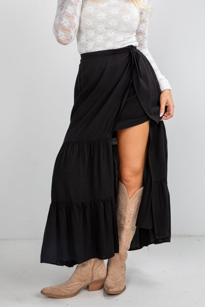 Person wearing a black tiered skirt with beige boots on a white background