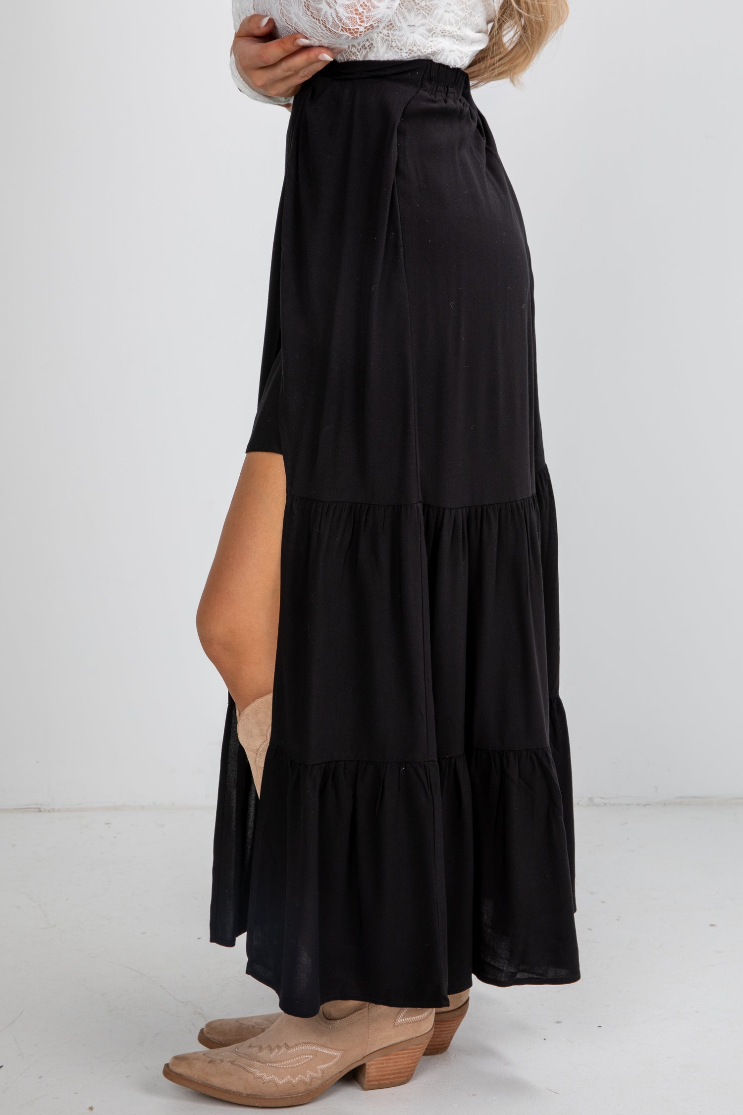 Black tiered maxi skirt with a slit on a white background
