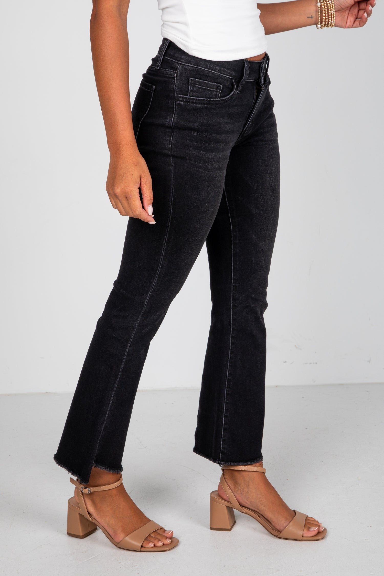 Person wearing black jeans and tan sandals on a white background