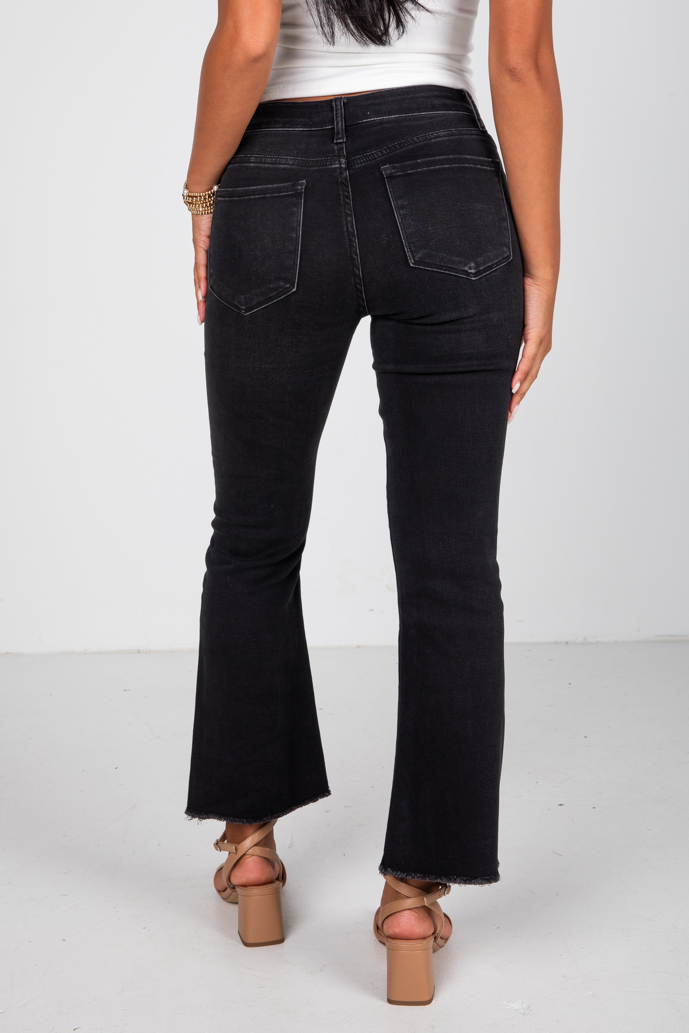 Black flared jeans worn by a person on a white background