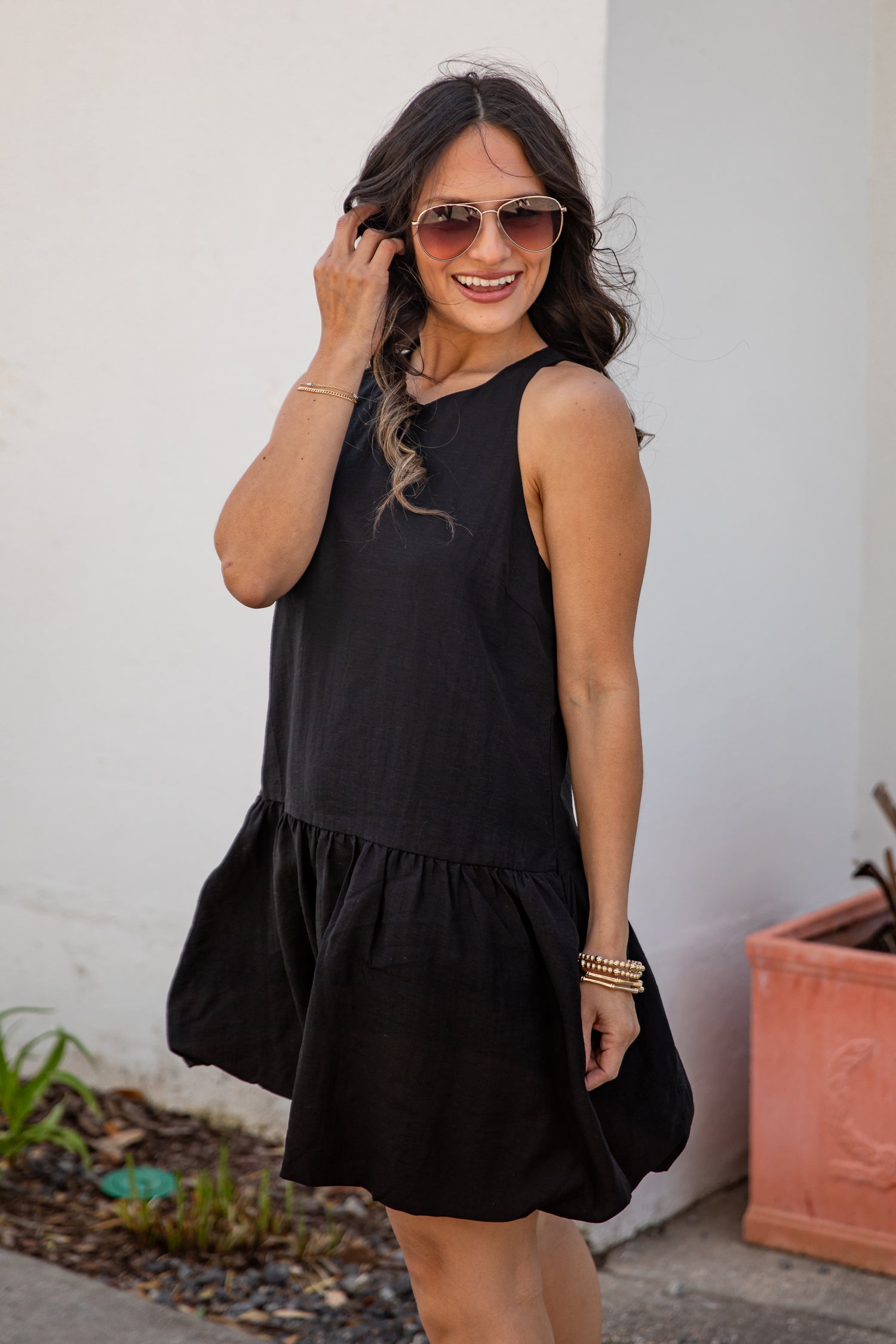 Woman wearing a black sleeveless dress with a white wall background