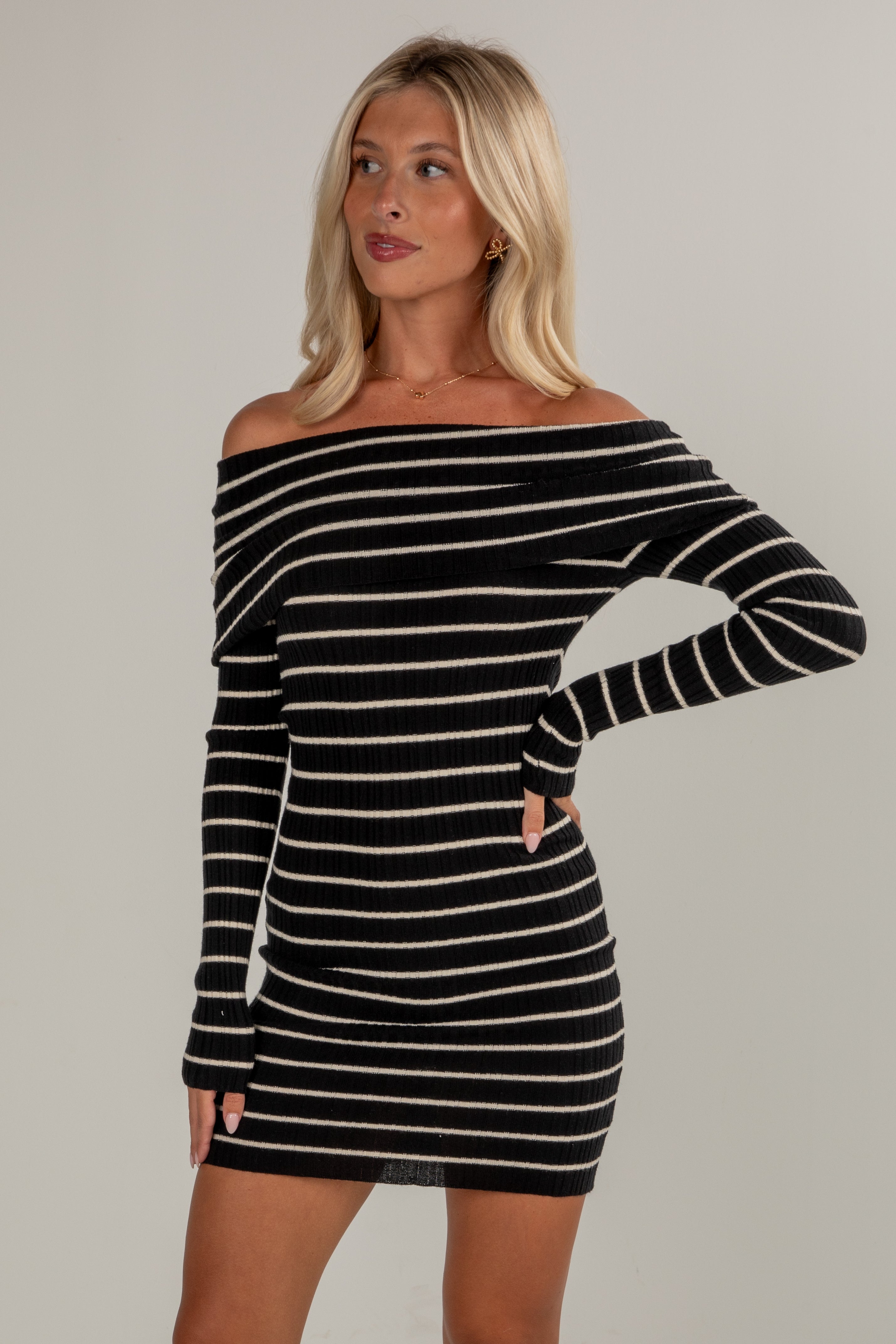 Woman wearing a black and white striped dress against a plain background