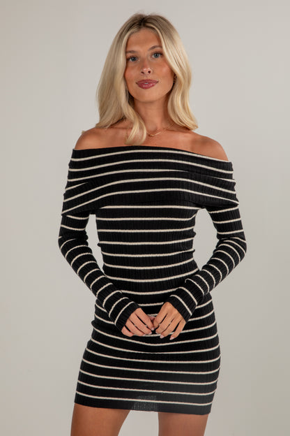 Woman wearing a black and white striped dress against a plain background