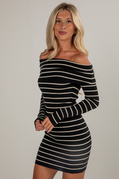 Woman wearing a black and white striped dress against a plain background