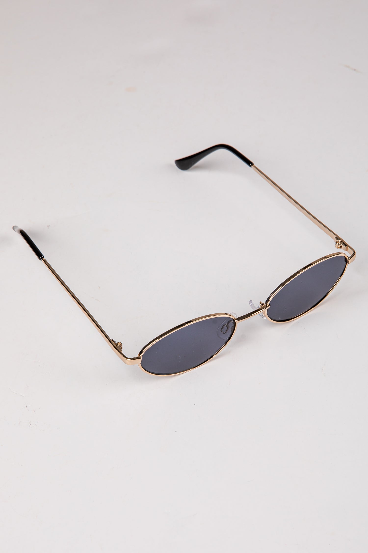 Sunglasses with gold frame and dark lenses on a white background