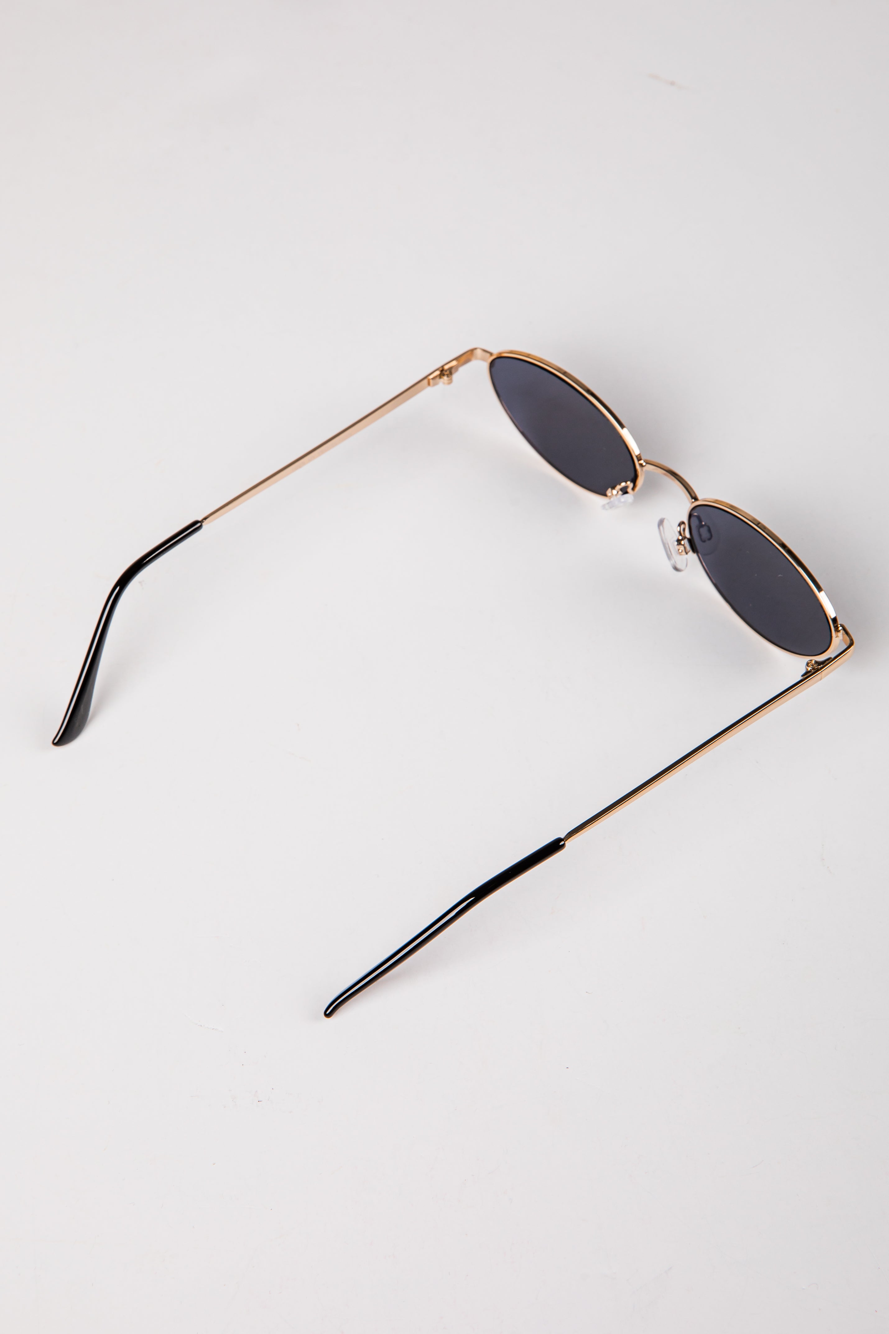Sunglasses with gold frame and dark lenses on a white background
