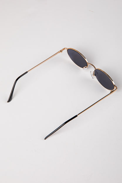 Sunglasses with gold frame and dark lenses on a white background