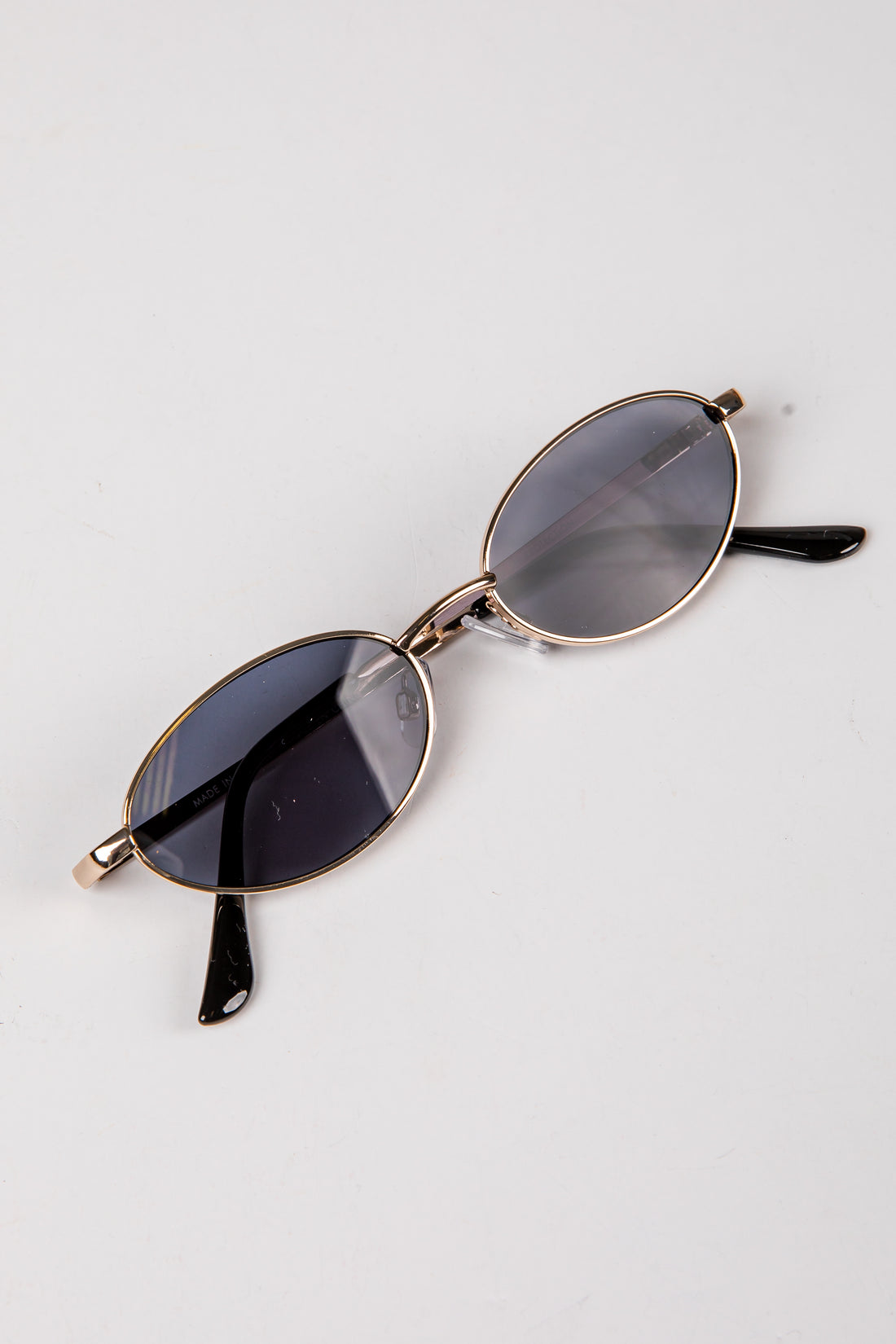 Sunglasses with gold frame and dark lenses on a white background