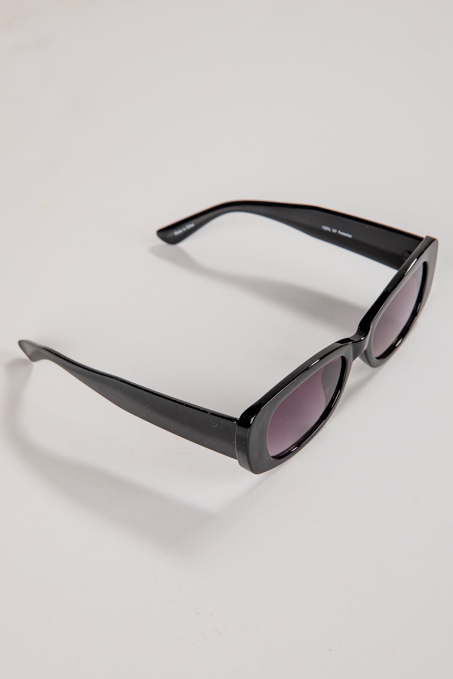 Black sunglasses with purple lenses on a light gray background