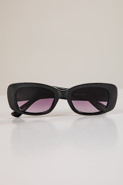 Black sunglasses with pink lenses on a light gray background