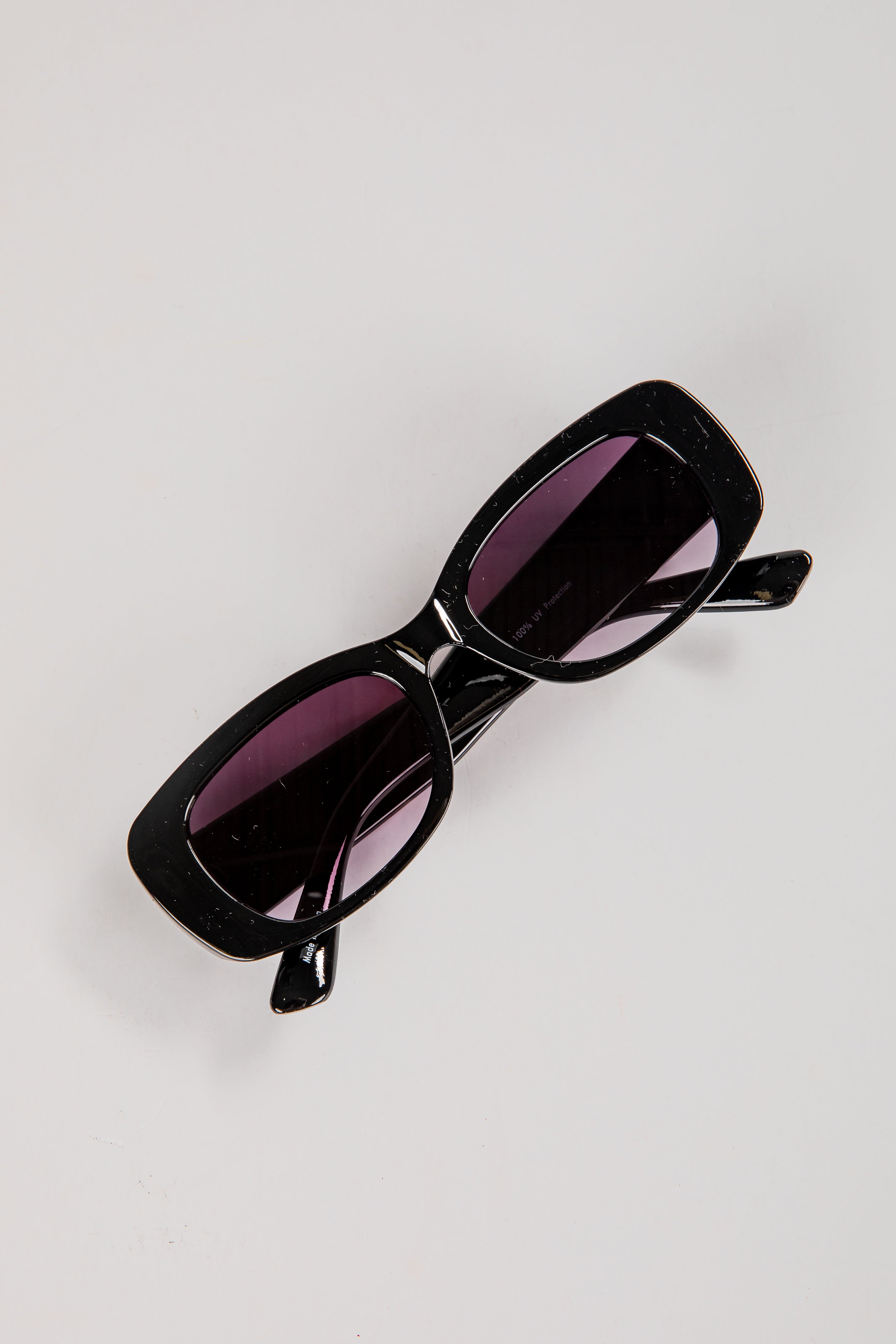 Black sunglasses with purple lenses on a light gray background