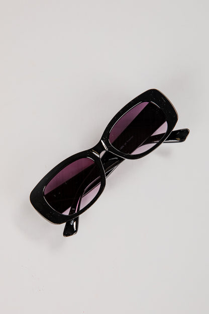 Black sunglasses with purple lenses on a light gray background