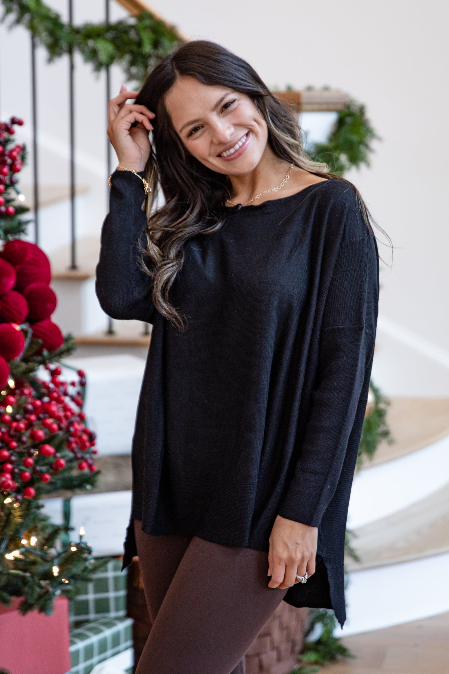 Woman wearing a black sweater standing in front of a decorated Christmas tree.