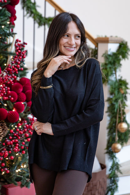 Woman in a black sweater standing in front of a decorated Christmas tree.