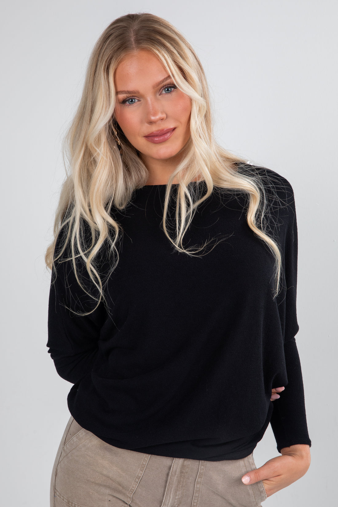 Woman wearing a black sweater with a spider web design on a plain background