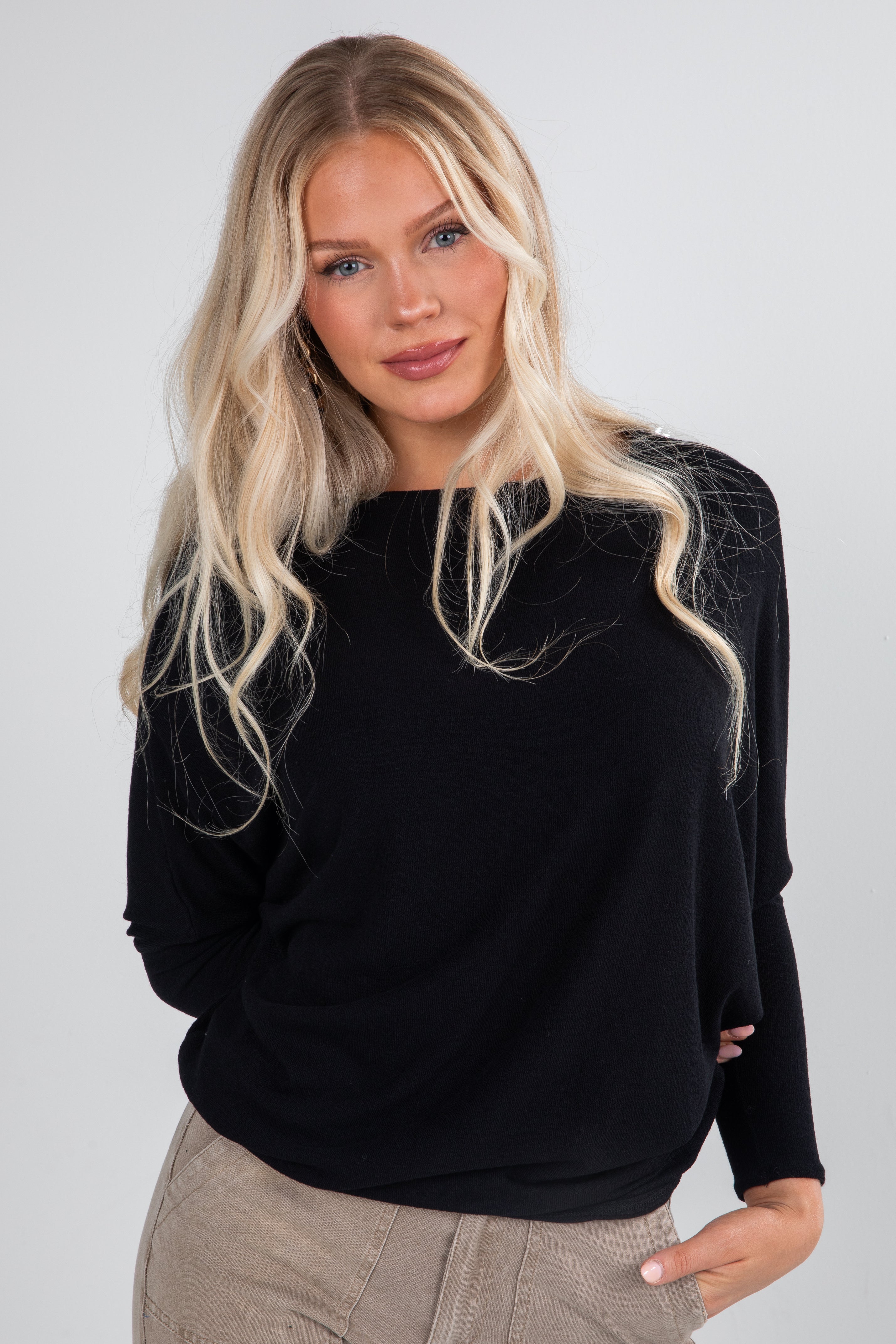 Woman wearing a black sweater with a spider web design on a plain background