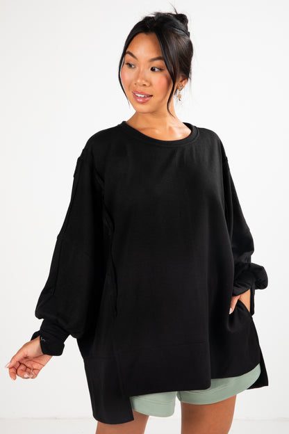 Woman wearing a black oversized sweater with green shorts on a white background