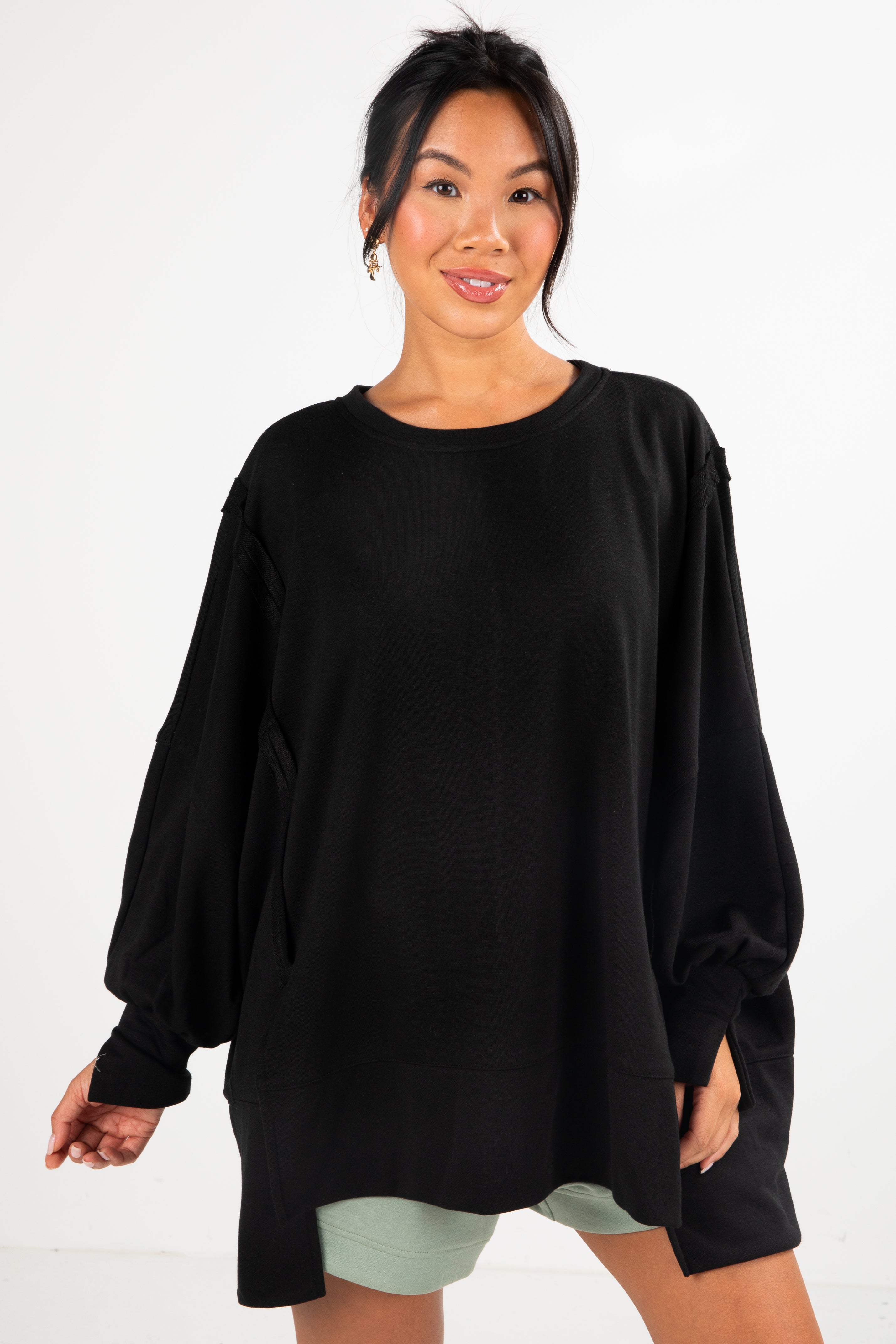Woman wearing a black oversized sweater on a white background