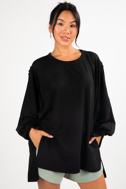 Woman wearing a black oversized top with a white background