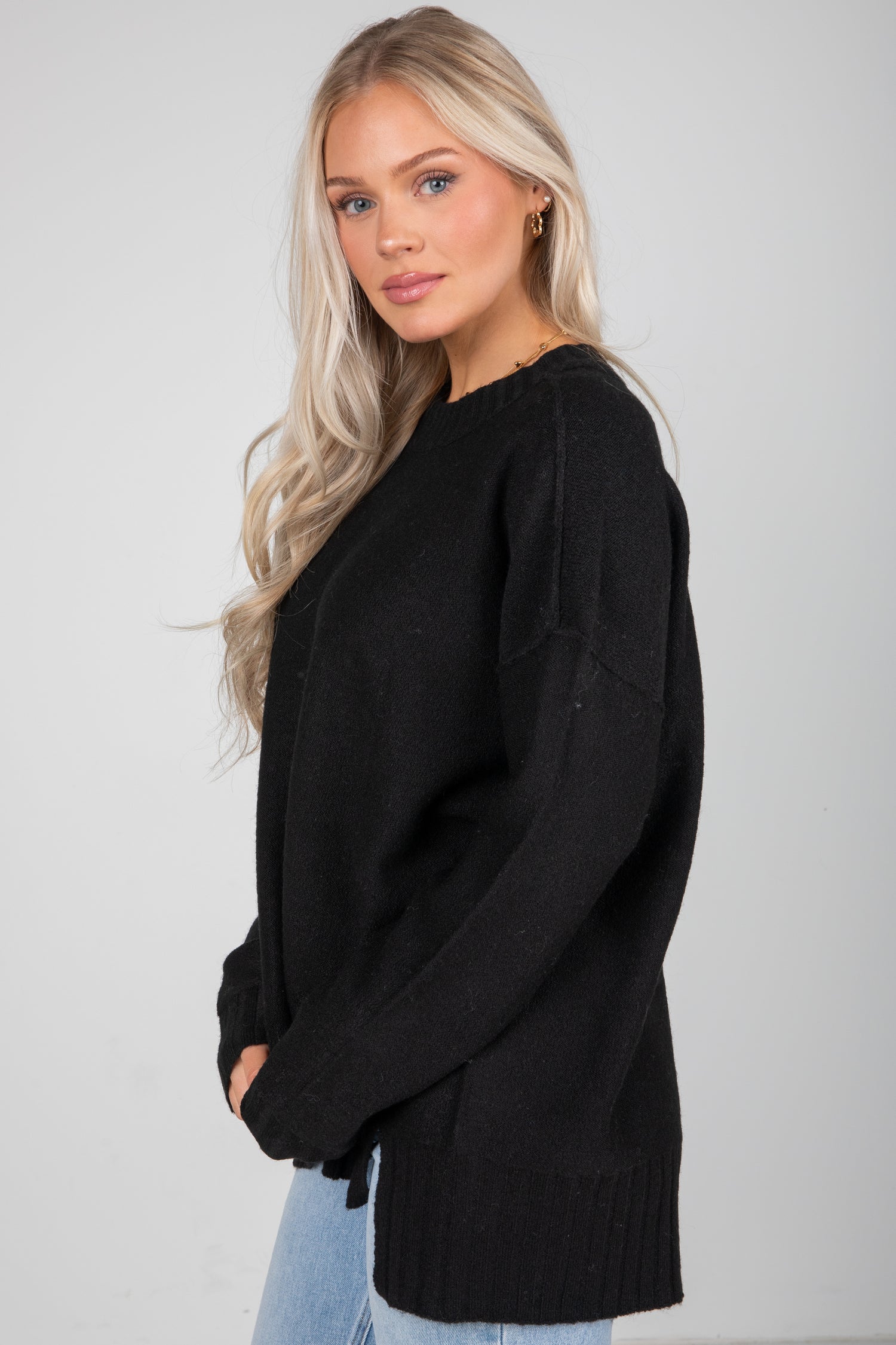 Woman wearing a black sweater against a plain background