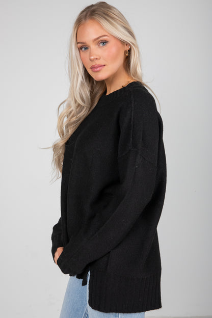 Woman wearing a black sweater against a plain background