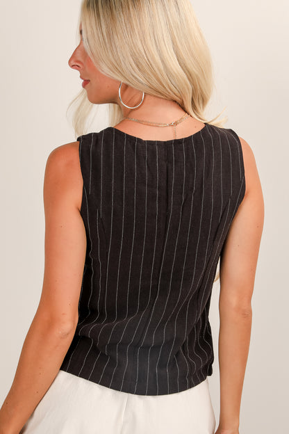 Woman wearing a black pinstripe sleeveless top against a plain background