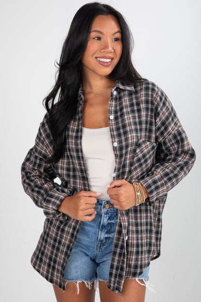 Woman wearing a plaid shirt over a white top and denim shorts on a white background