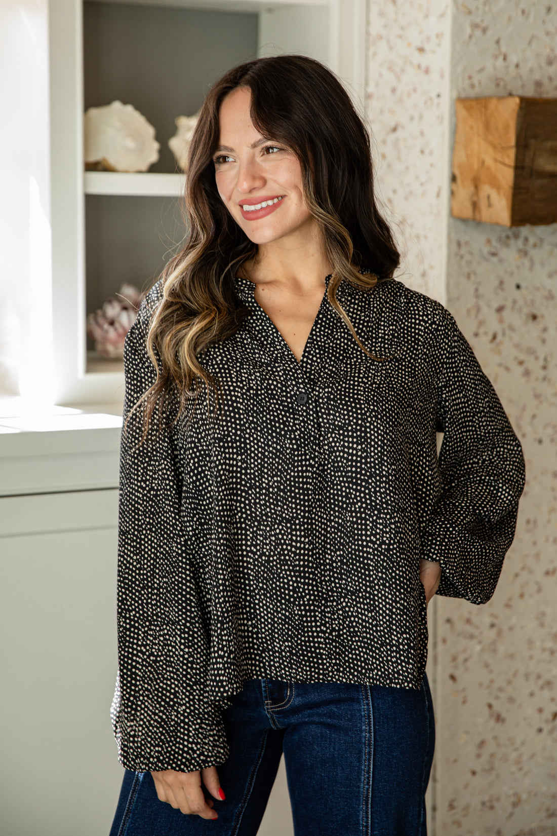 Woman wearing a black and white patterned blouse in an indoor setting