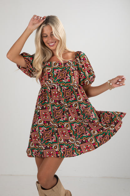 Woman wearing a patterned dress with puff sleeves on a plain background