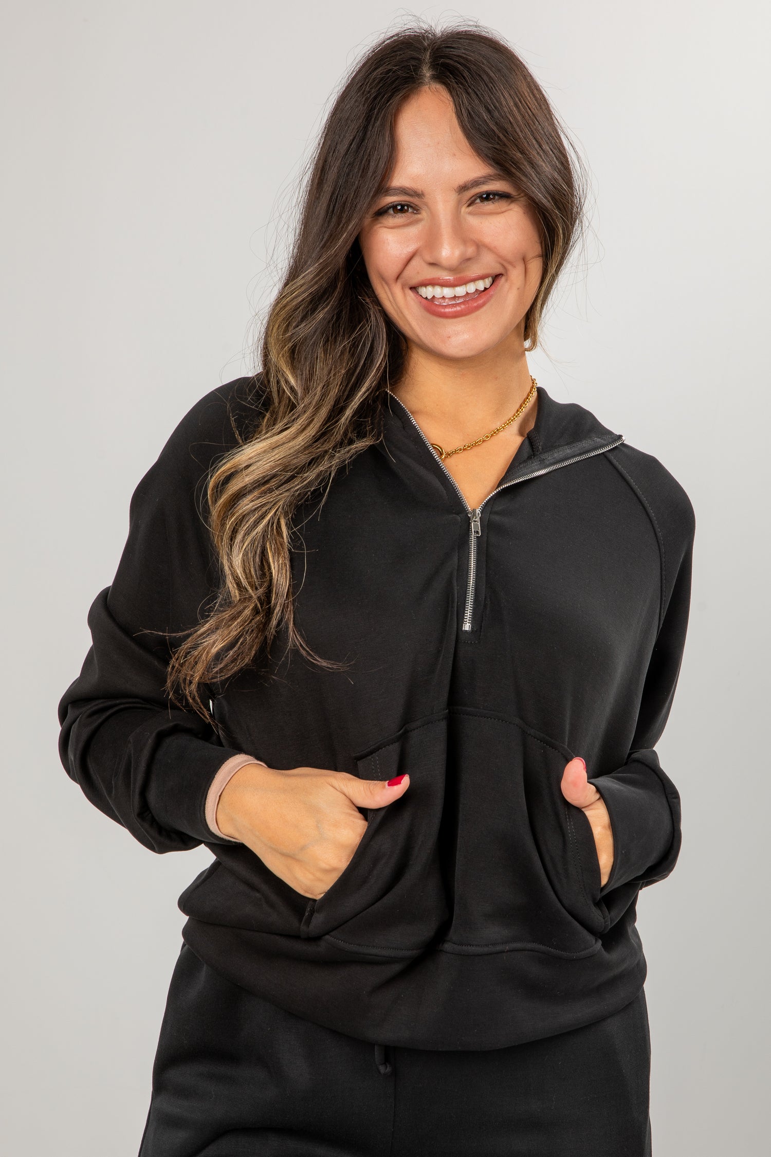 Woman wearing a black zip-up hoodie against a plain background
