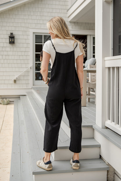 Woman in black overalls standing on a staircase outside a house