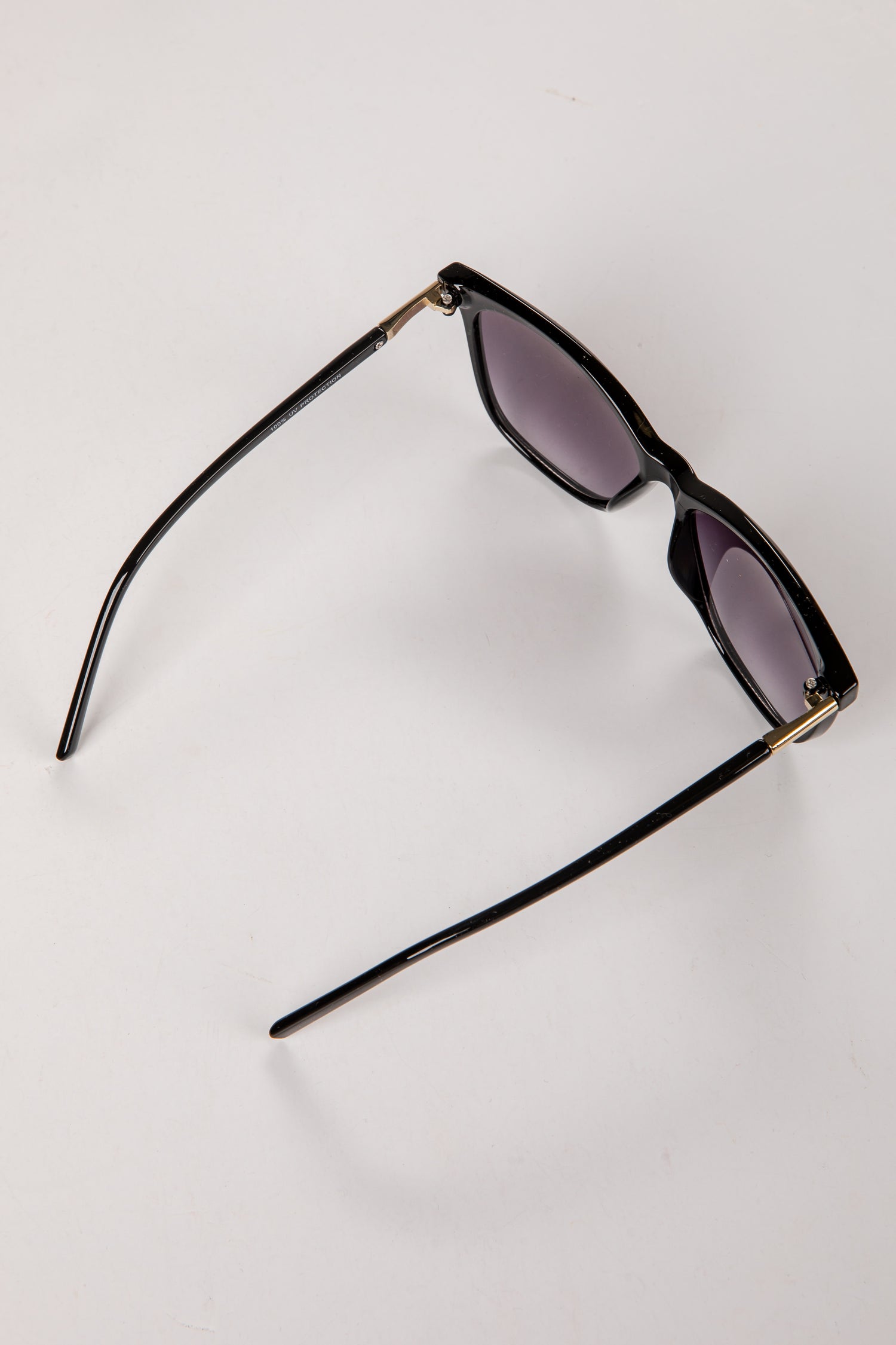 Black sunglasses with gold accents on a white background