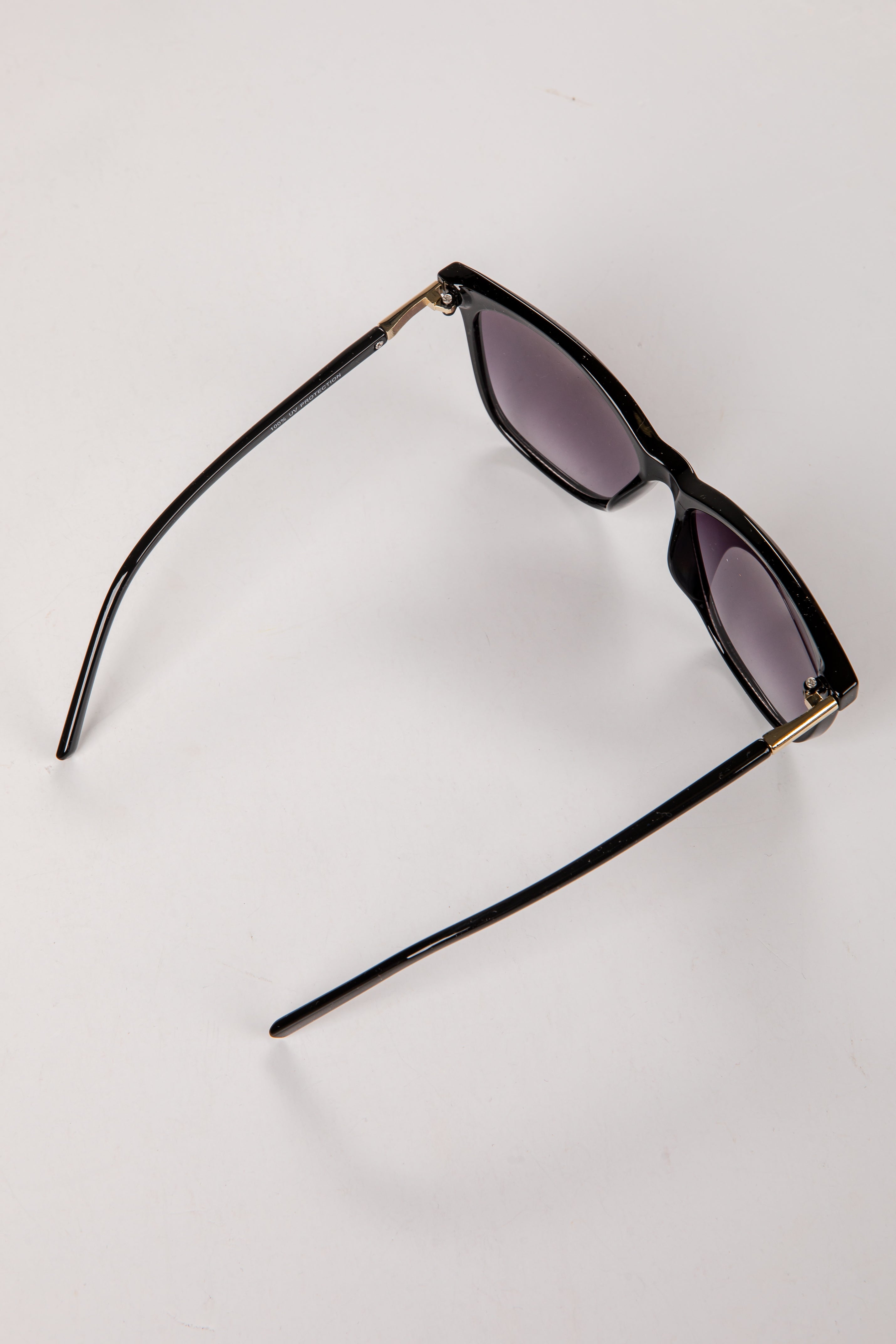 Black sunglasses with gold accents on a white background