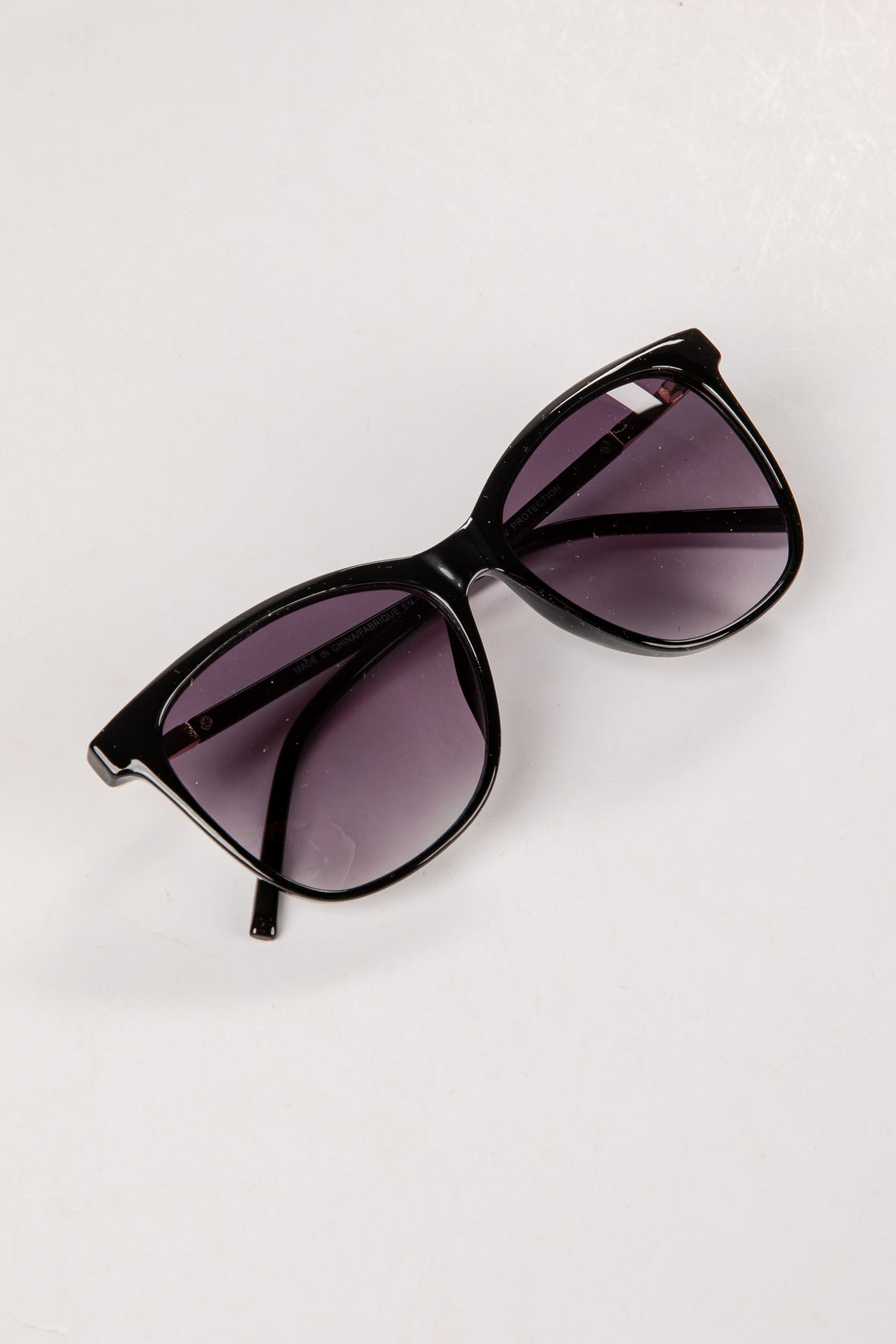 Black sunglasses with purple lenses on a white background
